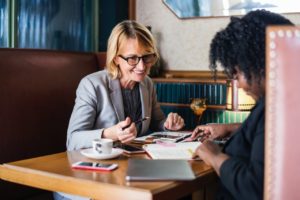 a blonde social security disability lawyer and client talk over papers in a restaurant booth