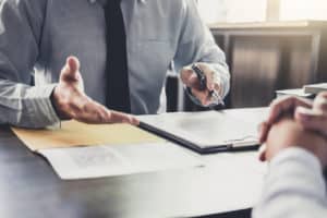 a man in a suit and tie gestures with his hands as a San Bernardino Social Security attorney explains how to apply for SS benefits